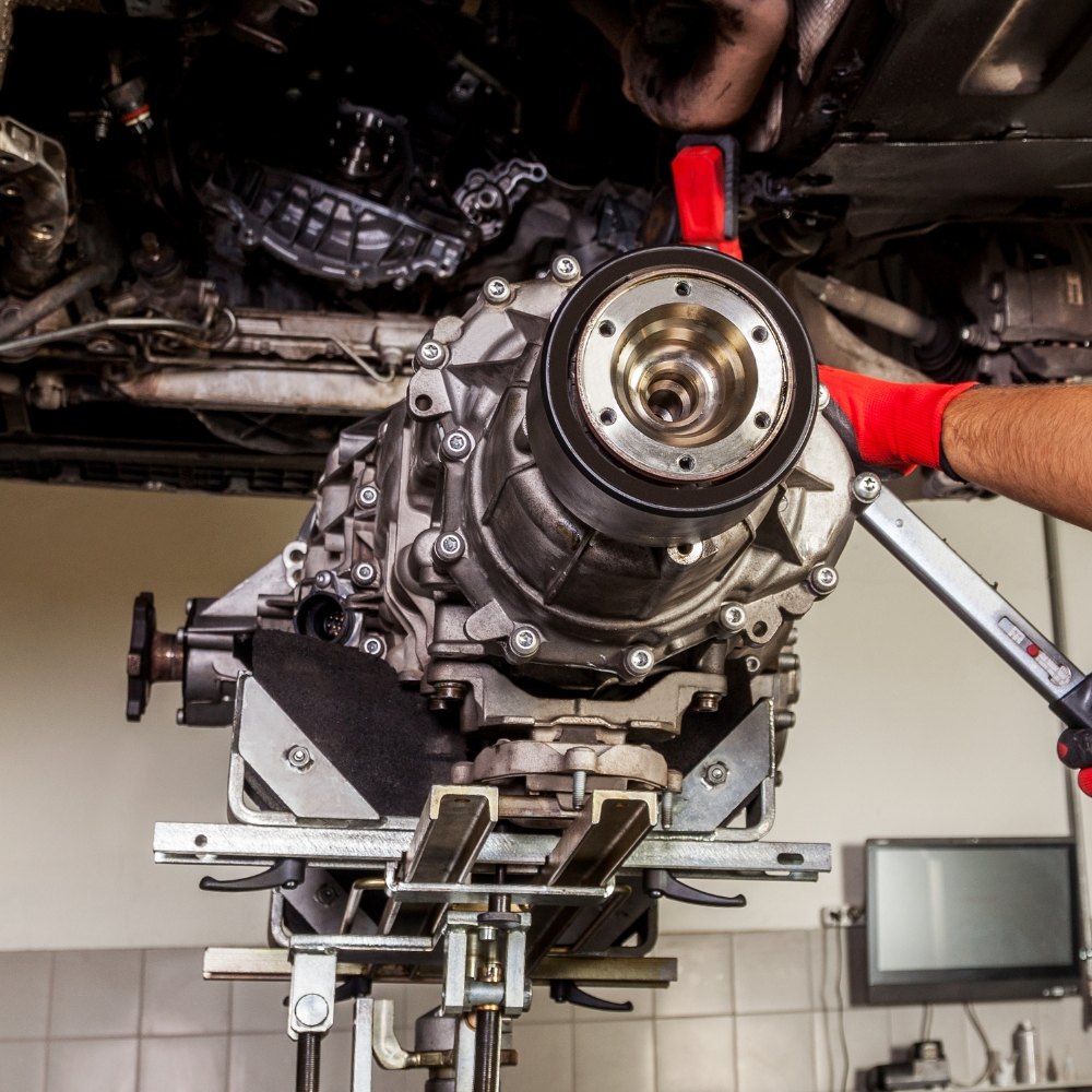 Gearbox being removed from a car on a transmission jack